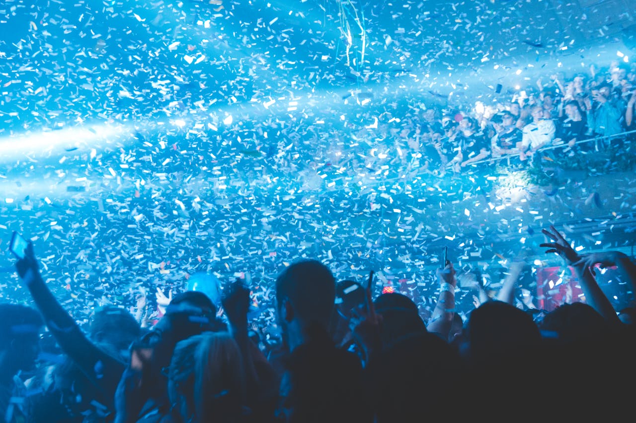 Vibrant nightclub scene with a lively crowd enjoying confetti and blue lights, capturing the essence of nightlife.